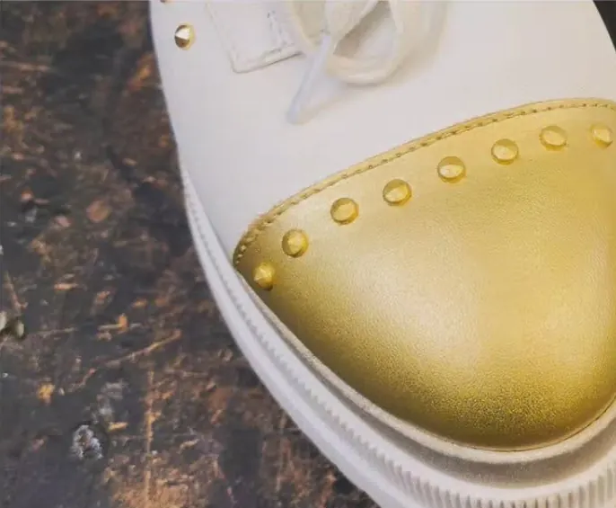 The same trainer with its gold toe cap rebuilt