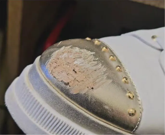White trainer with its gold leather toe cap peeling