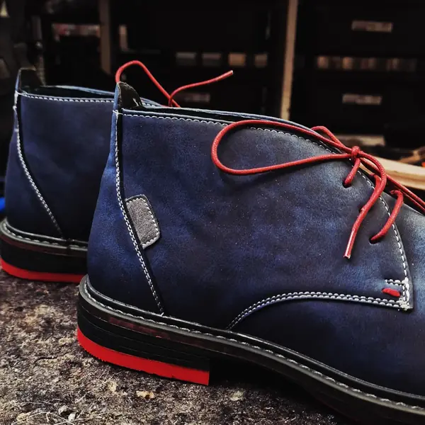 Blue suede chukka boots with red laces and soles