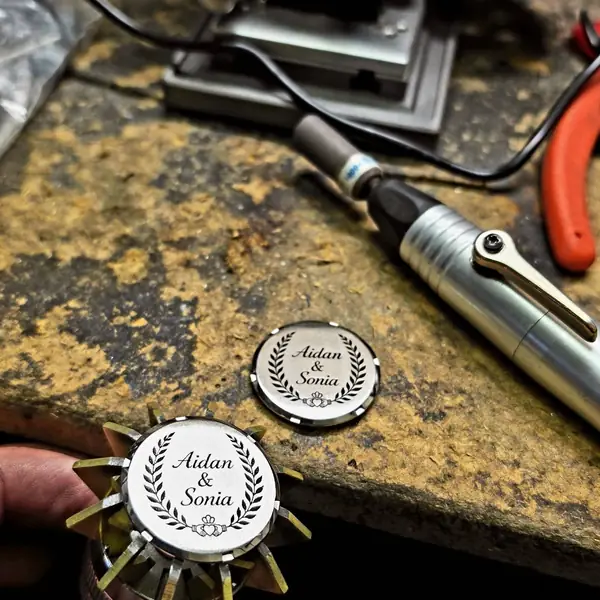 Two compact mirrors engraved ‘Aidan & Sonia’ beside the engraving tool