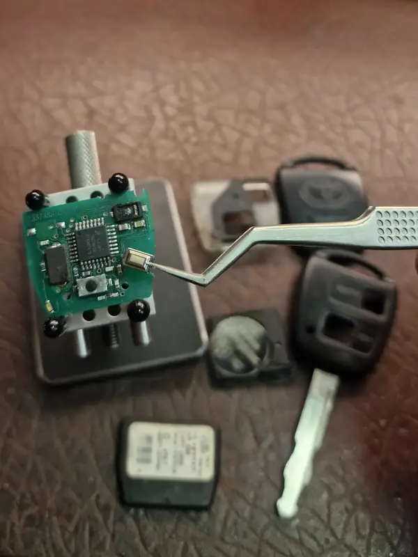 Fitting a new button to a Toyota remote’s circuit board, with the new key shell alongside